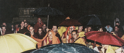 Lama Yeshe and Lama Zopa Rinpoche with Sangha and students doing puja in the rain, Bodhgaya, India, 1982.