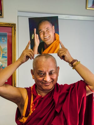 Lama Zopa Rinpoche holding a photo of Lama Yeshe. 