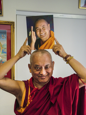 Lama Zopa Rinpoche holding a photo of Lama Yeshe. 