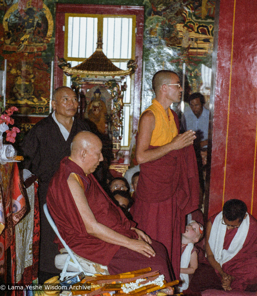 (23244_ng-3.psd) Ling Rinpoche teaching at the Tibetan Temple, Bodhgaya, India, 1982. Lozang Kunrig (Thubten Tsering- Ling Rinpoche attendant) on left, Bruno LeGuevel standing center, Lama Zopa Rinpoche seated, head lowered.