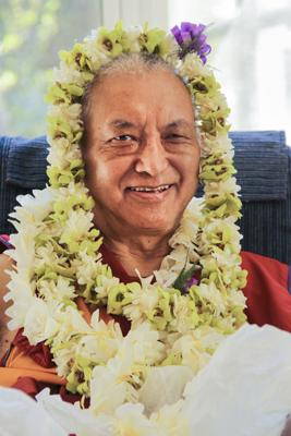 Lama Zopa Rinpoche adorned with flowers, 2010.