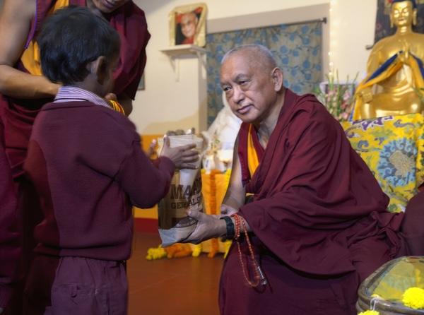 Lama Zopa Rinpoche offering food to a young student at Maitreya School in Bodhgaya, India