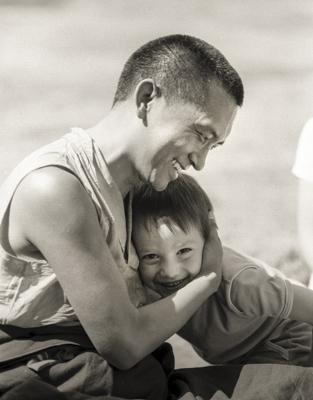 Lama Zopa Rinpoche hugs a child while relaxing with students at Waterlow Park, Highgate, London, 1983. Photo: Robin Bath.