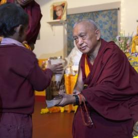 Lama Zopa Rinpoche offering food to a young student at Maitreya School in Bodhgaya, India